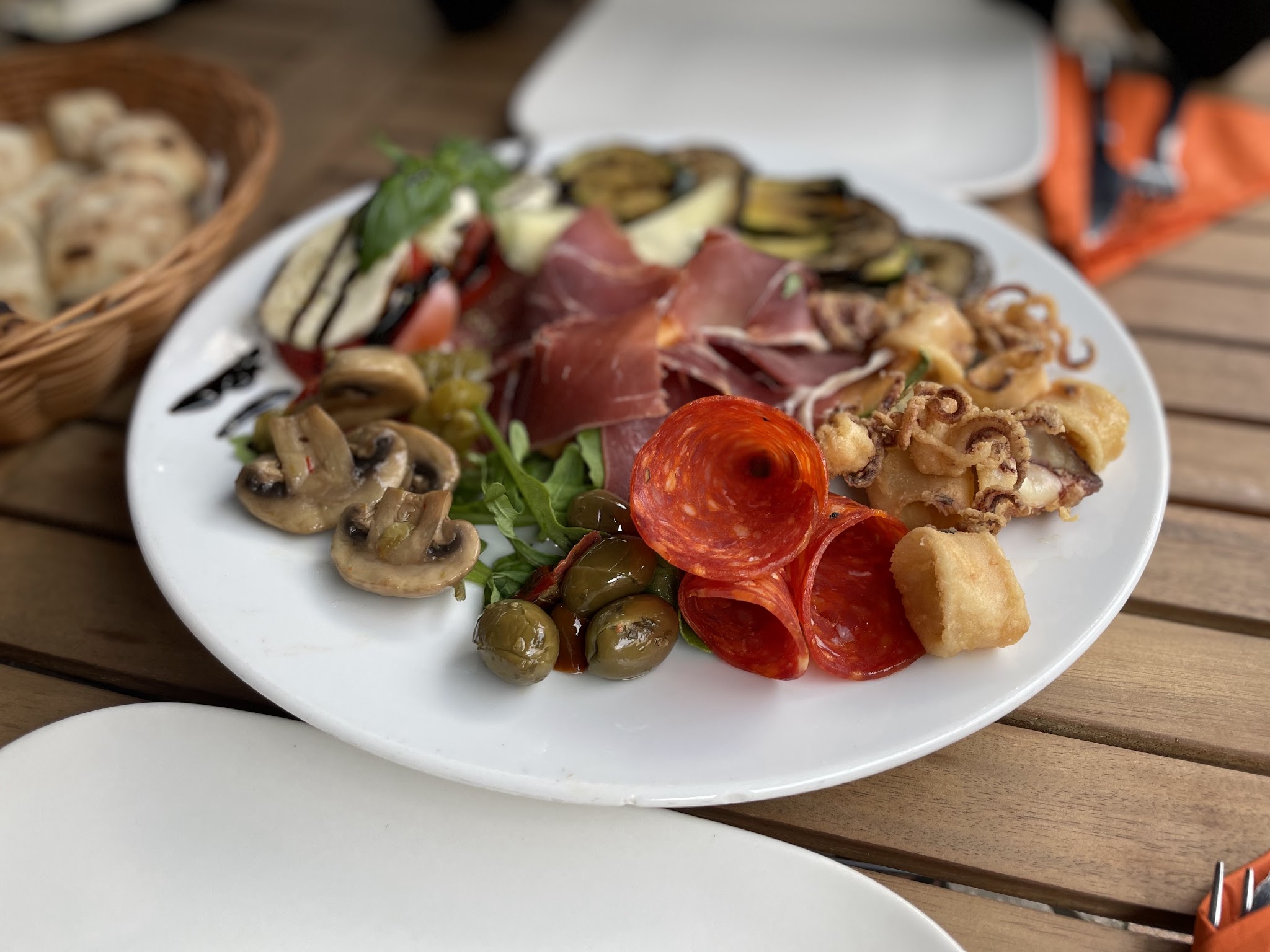 Antipasti-Teller mit Parmaschinken, Salami, gegrilltem Gemüse und Calamari fritti