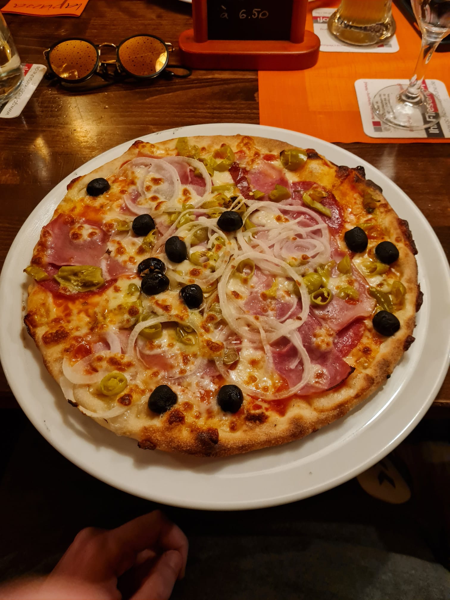 Pizza mit Schinken, Zwiebeln, Peperoni und schwarzen Oliven